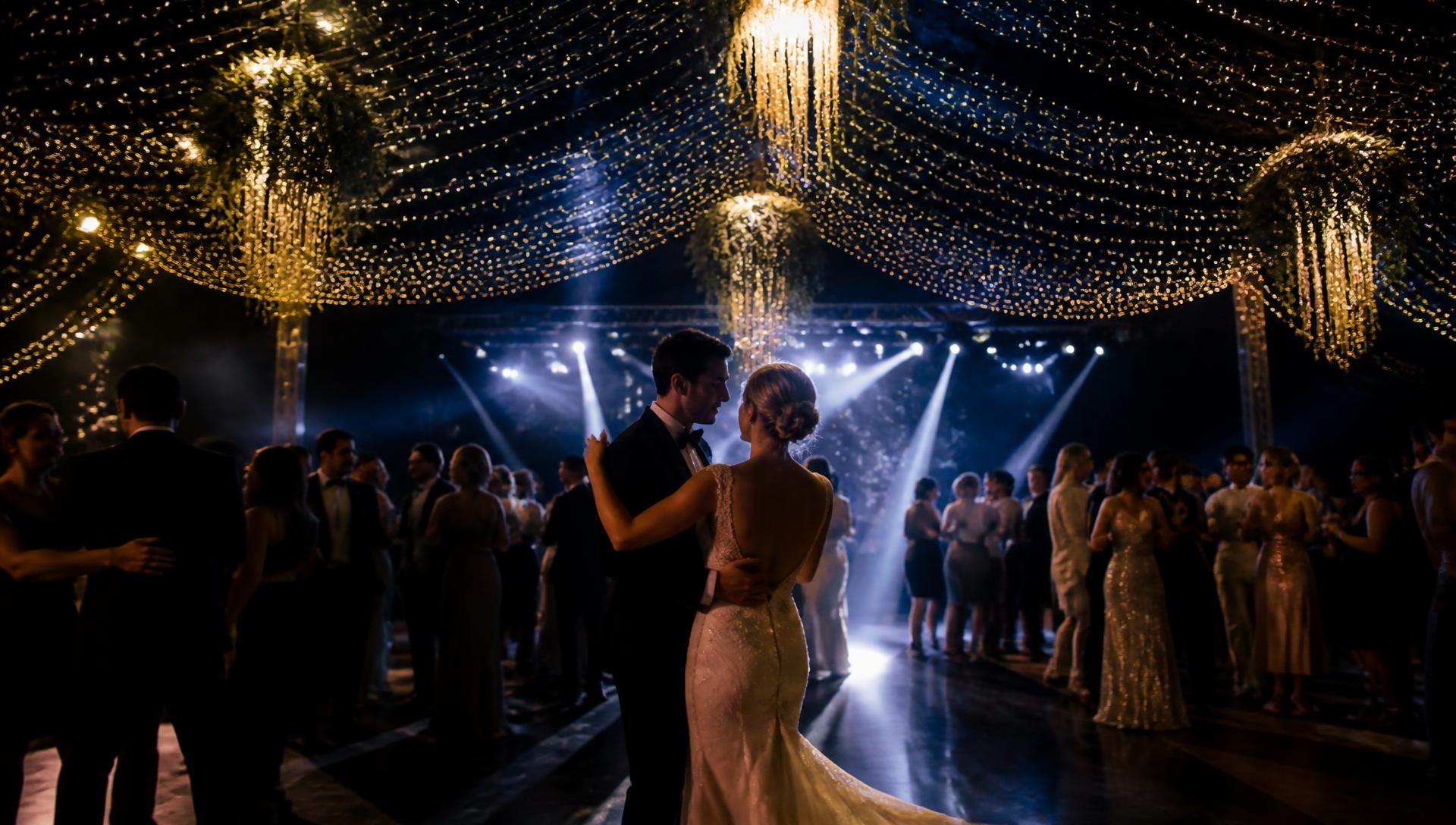 Guests dancing beneath gold festoon lighting at an evening reception